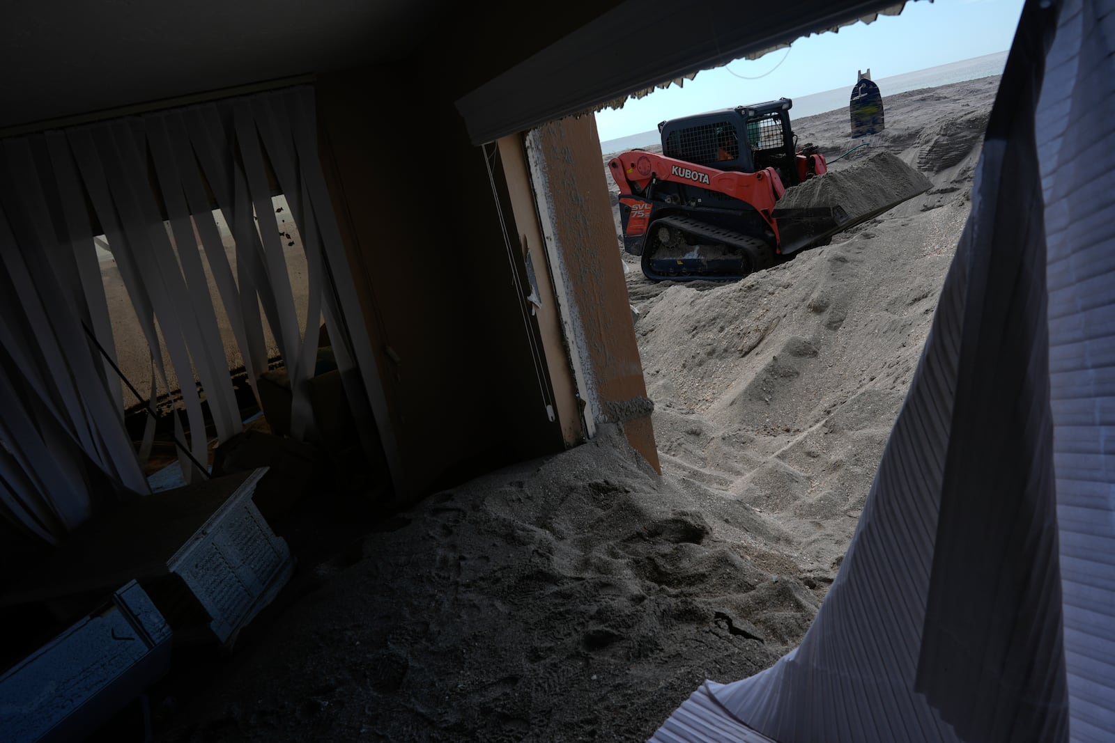 Scott Bennett, a contractor who specializes in storm recovery, removes sand around 5 feet deep from the patio of a beachfront condominium in Venice, Fla.,following the passage of Hurricane Milton, Saturday, Oct. 12, 2024. (AP Photo/Rebecca Blackwell)