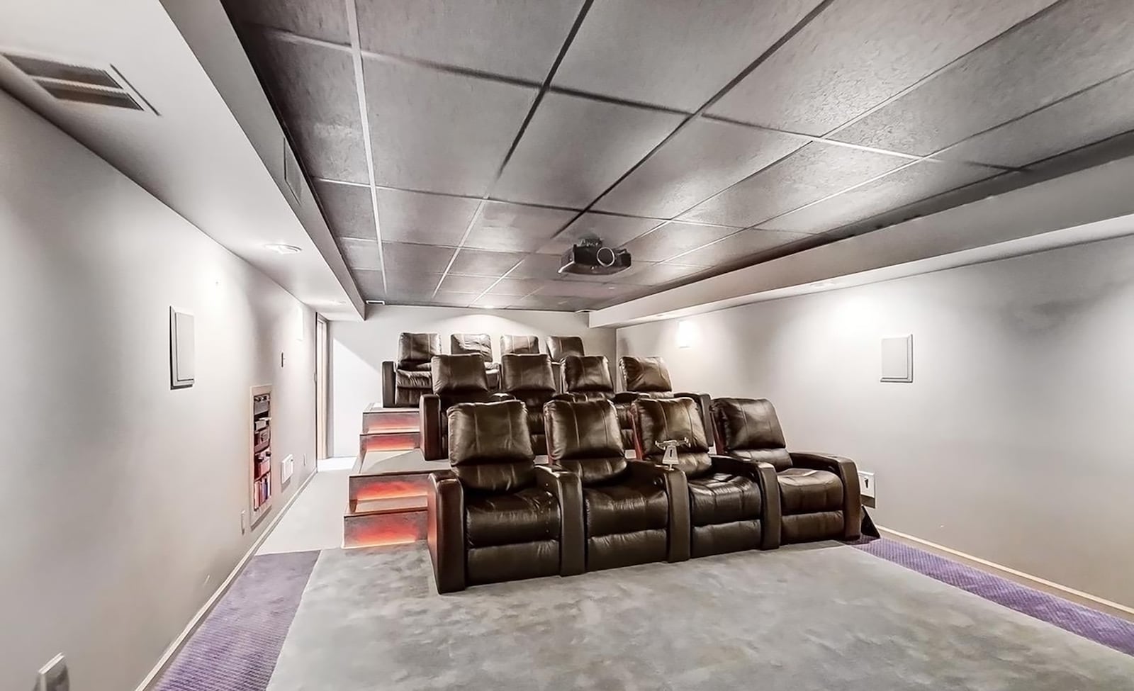 The basement level theater room has twelve reclining theater chairs on separate levels, a screen and projector.