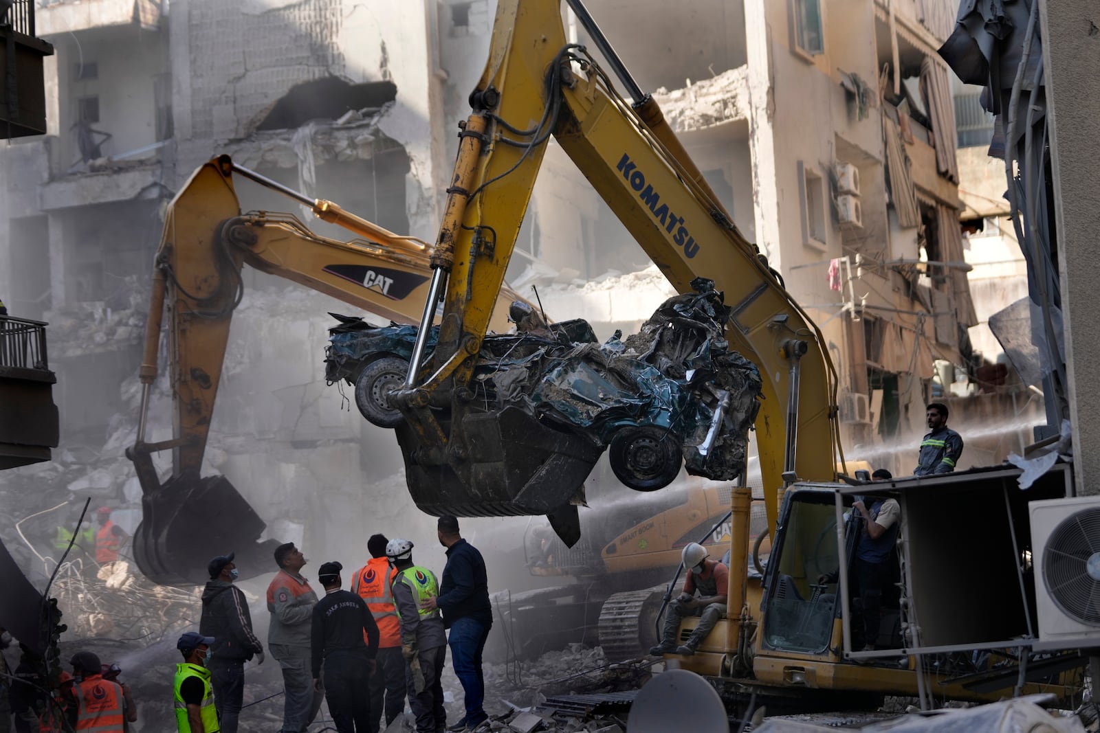 An excavator removes a destroyed car as rescue workers gather at the site of an Israeli airstrike that hit central Beirut, Lebanon, Saturday, Nov. 23, 2024. (AP Photo/Hussein Malla)