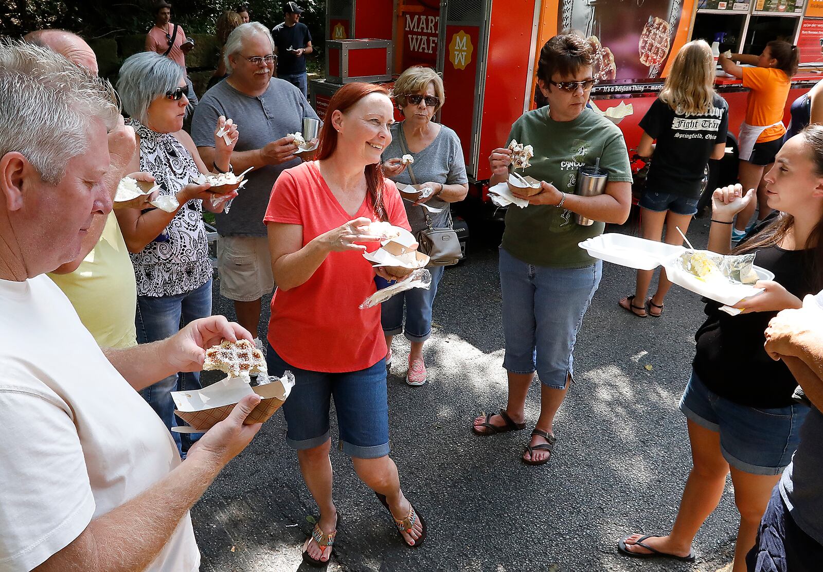 A group of people talk as they enjoy waffles beside the Marty's Waffles food truck at the Springfield Rotary Food Truck Competition Saturday at Veteran's Park. Bill Lackey/Staff