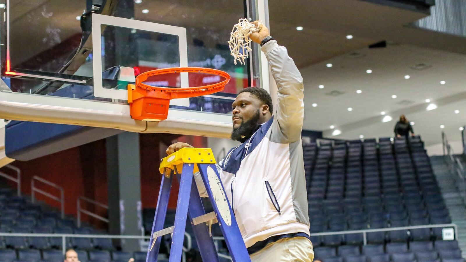 Springfield High School coach Isaiah Carson raises the net in celebration after his team beat Elder 55-35 to win its third straight district title on Saturday night at the University of Dayton Arena. CONTRIBUTED PHOTO BY MICHAEL COOPER