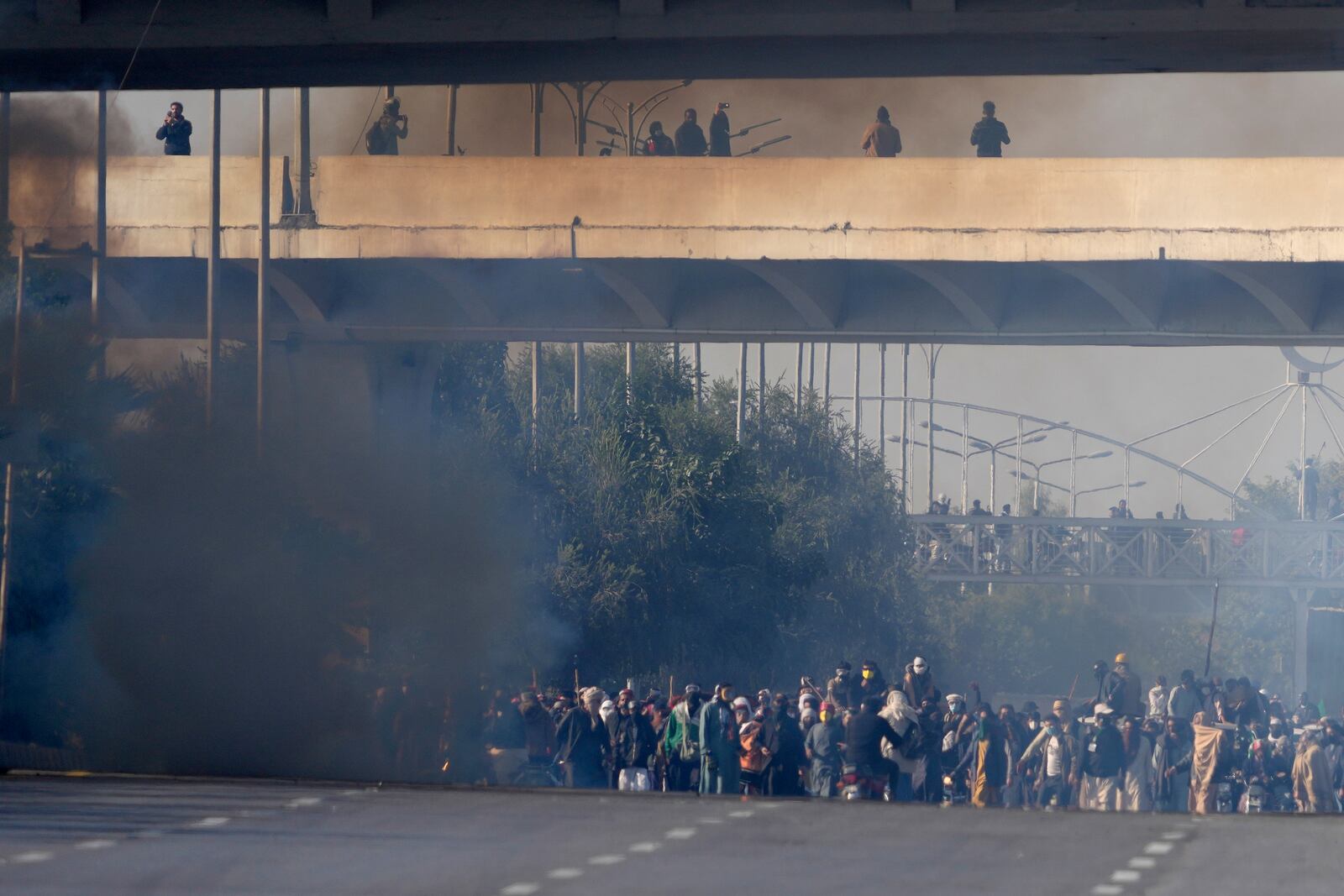 Supporters of imprisoned former Premier Imran Khan's Pakistan Tehreek-e-Insaf party move forwards following police fire tear gas shells to disperse them during clashes in Islamabad, Pakistan, Tuesday, Nov. 26, 2024. (AP Photo/Anjum Naveed)