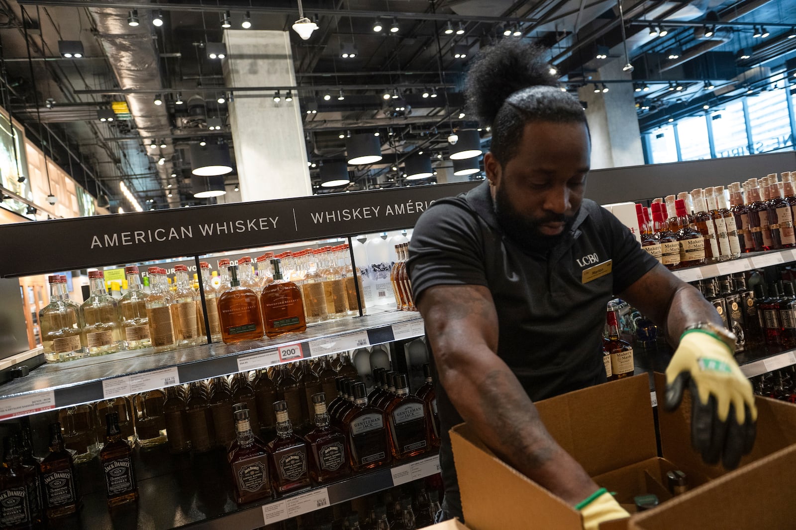 An LCBO employee removes American whiskey from the shelves at the 100 Queens Quay East LCBO outlet in Toronto on Tuesday, March 4, 2025. (Laura Proctor /The Canadian Press via AP)