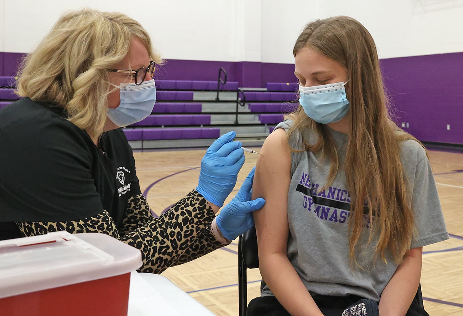 Mechanicsburg student Lily Eck, who just turned 16 two days earlier, gets the COVID vaccine from Hope Stickley, a nurse from the Champaign County Health Department, Thursday during a COVID clinic in one of the Mechanicsburg gymnasiums. BILL LACKEY/STAFF