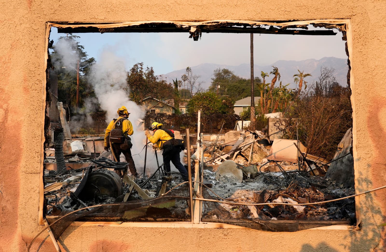 Firefighters extinguish burning embers at a house on Santa Rosa Avenue, also known as Christmas Tree Lane, Thursday, Jan. 9, 2025, in Altadena, Calif. (AP Photo/Chris Pizzello)