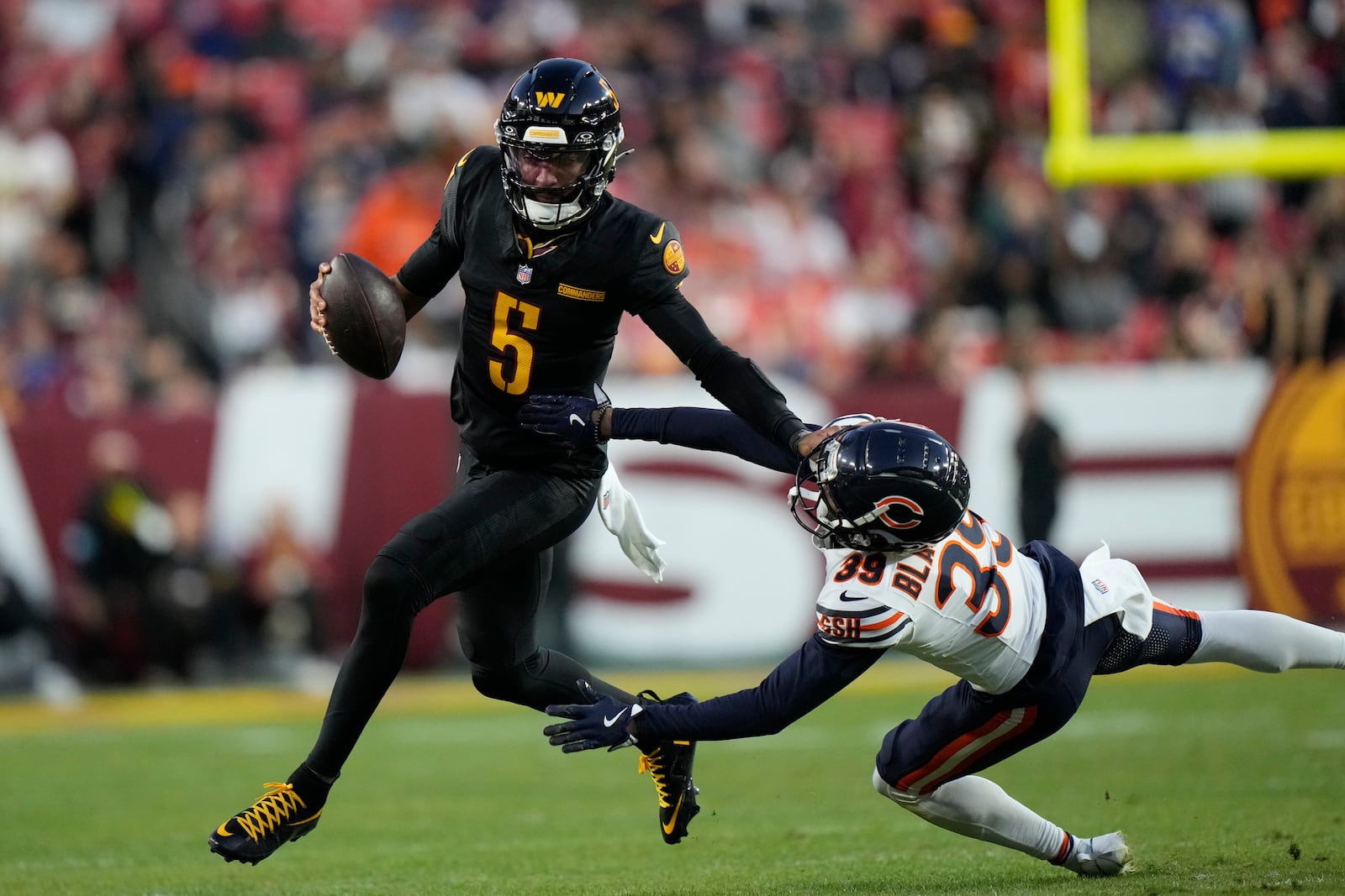 Washington Commanders quarterback Jayden Daniels (5) scrambles past Chicago Bears cornerback Josh Blackwell (39) in the second half of an NFL football game Sunday, Oct. 27, 2024, in Landover, Md. (AP Photo/Stephanie Scarbrough)