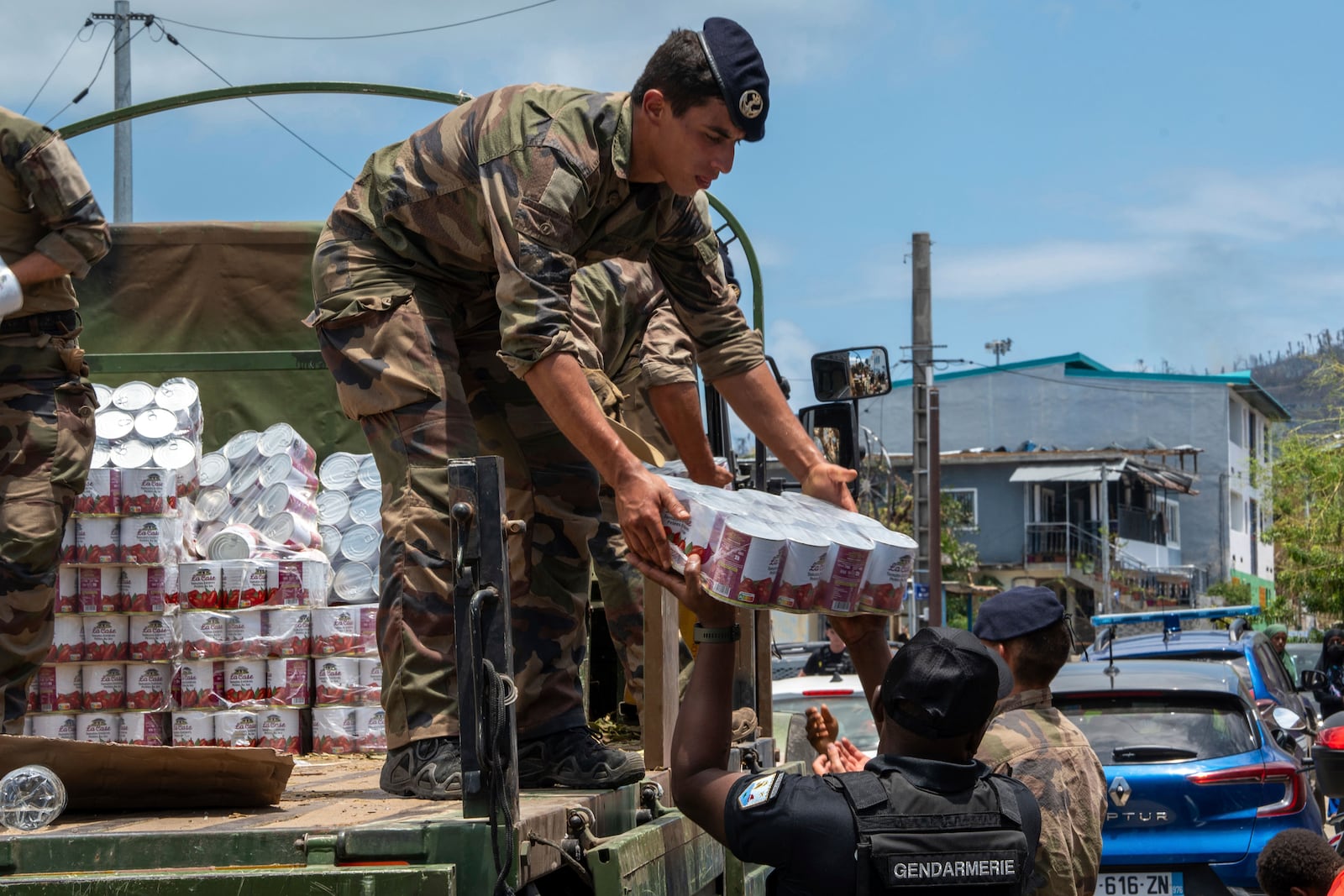 This photo provided by the French Army shows a soldier unloading cans of food in the Indian Ocean French territory of Mayotte, Wednesday Dec.18, 2024, as the cyclone on Saturday was the deadliest storm to strike the territory in nearly a century. (D Piatacrrea, Etat Major des Armees/Legion Etrangere via AP)