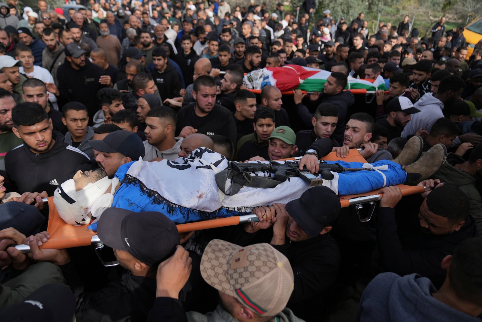 Mourners carry the bodies of eight killed Palestinians, some wrapped with the Islamic Jihad flag, during their funeral following the withdrawal of the Israeli army, in the West Bank city of Tulkarem, Thursday, Dec. 26, 2024. (AP Photo/Nasser Nasser)