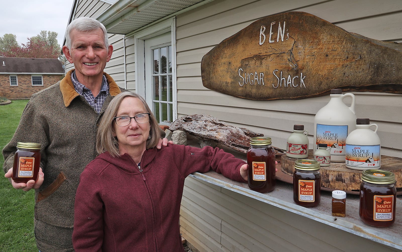 Ben and Deb Hamilton with some of their delicious maple syrup Thursday outside their backyard sugar shack. BILL LACKEY/STAFF