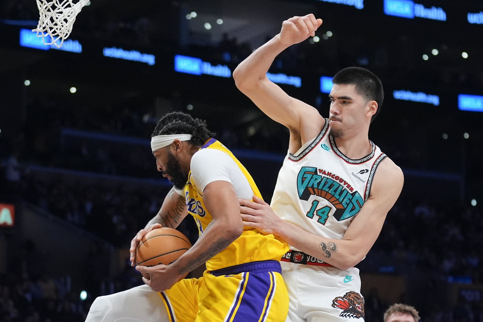 Los Angeles Lakers forward Anthony Davis, left, grabs a rebound over Memphis Grizzlies center Zach Edey (14) during the first half of an NBA basketball game Wednesday, Nov. 13, 2024, in Los Angeles. (AP Photo/Marcio Jose Sanchez)