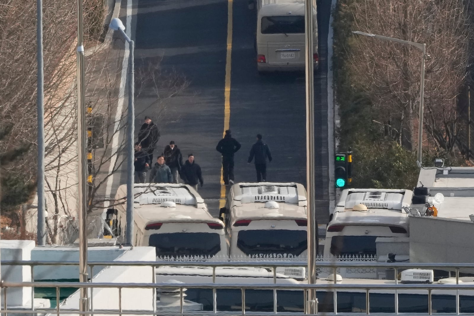 Security personnel walk on a road lined up with buses blocking the entrance gate of impeached South Korean president Yoon Suk Yeol's residence in Seoul, South Korea, Wednesday, Jan. 8, 2025. (AP Photo/Ahn Young-joon)