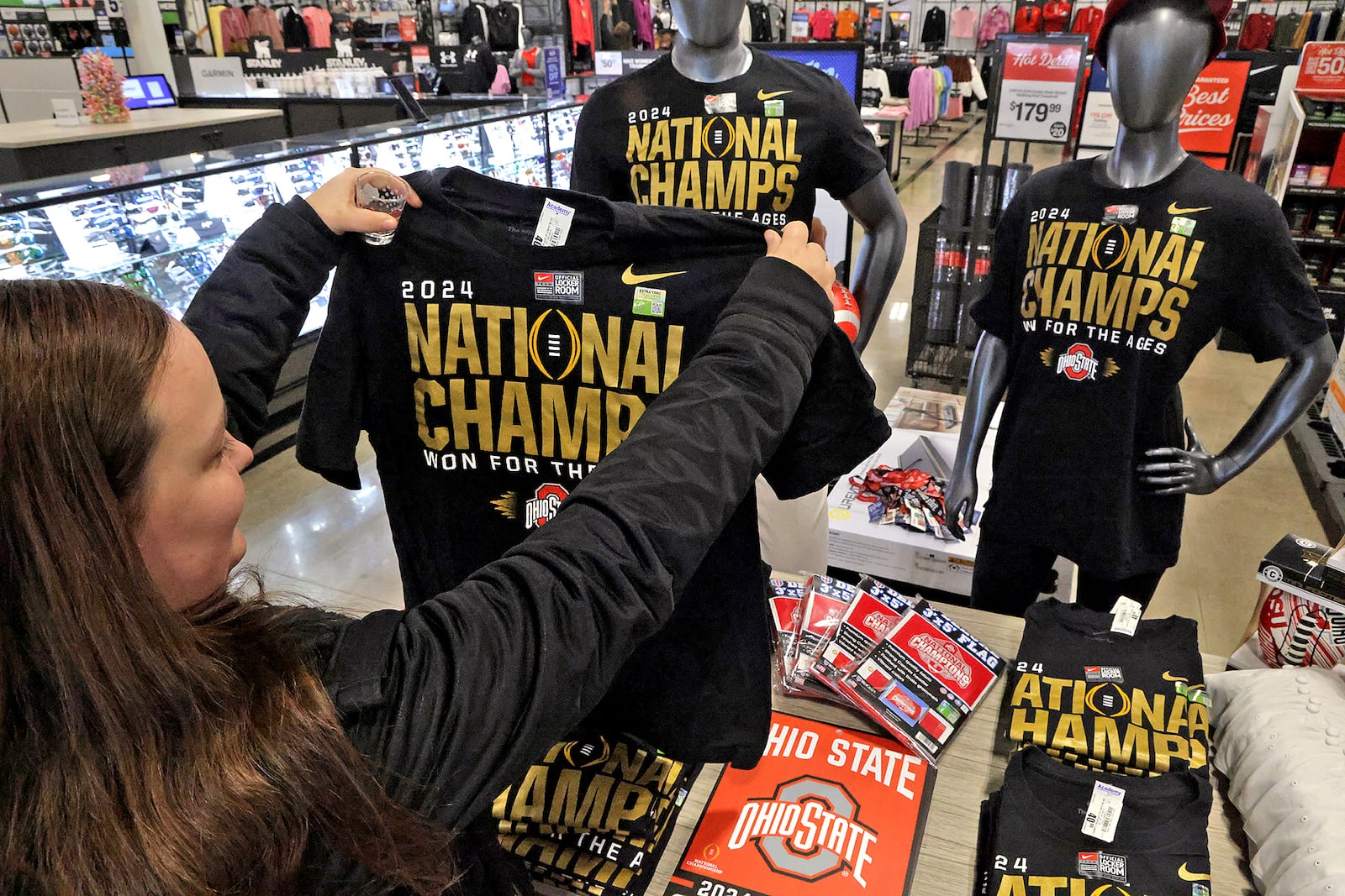 Maddie Lyday looks over a "National Champs" shirt as she shops for Ohio State National Champions merchandise at Academy Sports in Springfield Tuesday, Jan. 21, 2025. BILL LACKEY/STAFF