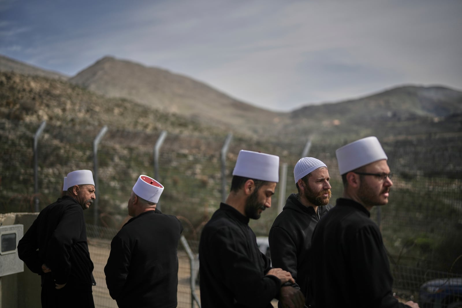 Druze clerics stand near the border, as they wait for buses carrying members of the Syrian Druze community to cross from Syria in the village of Majdal Shams, in the Israeli-controlled Golan Heights, Friday, March 14, 2025. (AP Photo/Leo Correa)