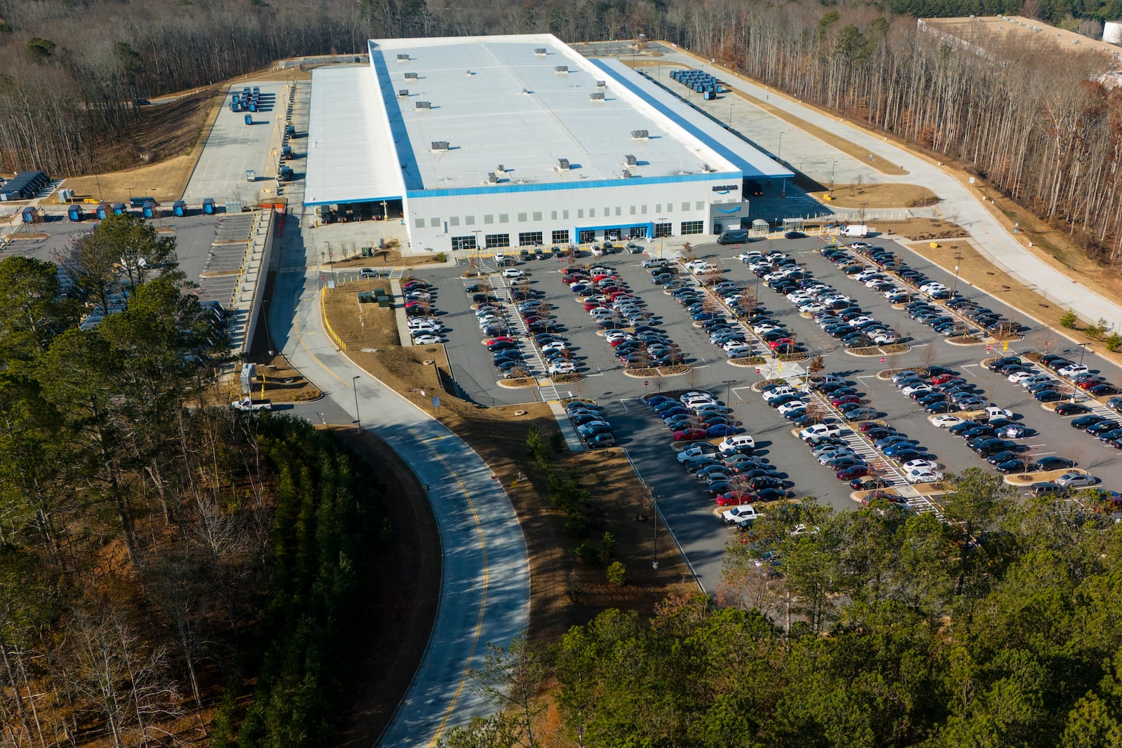 An Amazon warehouse is seen as pro-union protesters march outside the facility, Friday, Dec. 20, 2024, in Alpharetta, Ga. (AP Photo/=6TVFL7C0M2X2PH=)