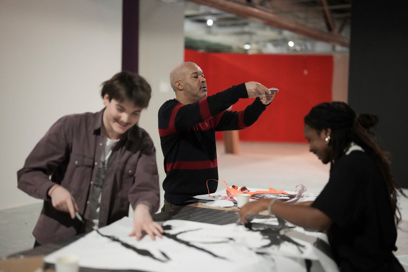 French street artist Shuck One takes a snapshot of one of his drawing during the preparation of the exhibition "Paris Noir", at the Centre Pompidou Museum, in Paris, Tuesday, Feb. 18, 2025. (AP Photo/Thibault Camus)