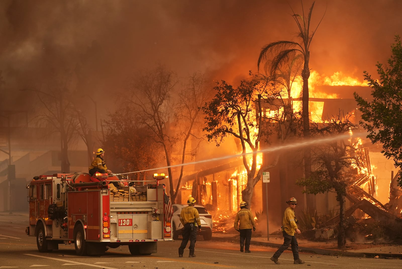 Firefighters hose down a burning structure on Lake Avenue, Wednesday, Jan. 8, 2025, in the downtown Altadena section of Pasadena, Calif. (AP Photo/Chris Pizzello)