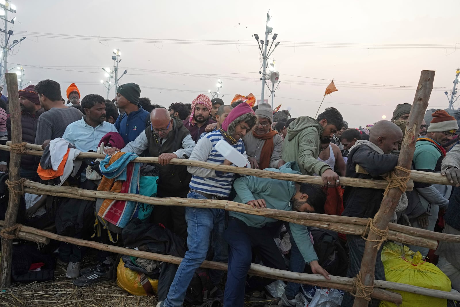 Hindu devotees try to cross a barricade to take a holy dip in the Sangam, the confluence of the Ganges, the Yamuna and the mythical Saraswati rivers, on "Mauni Amavasya" or new moon day during the Maha Kumbh festival in Prayagraj, India, Wednesday, Jan. 29, 2025. (AP Photo/Rajesh Kumar Singh)