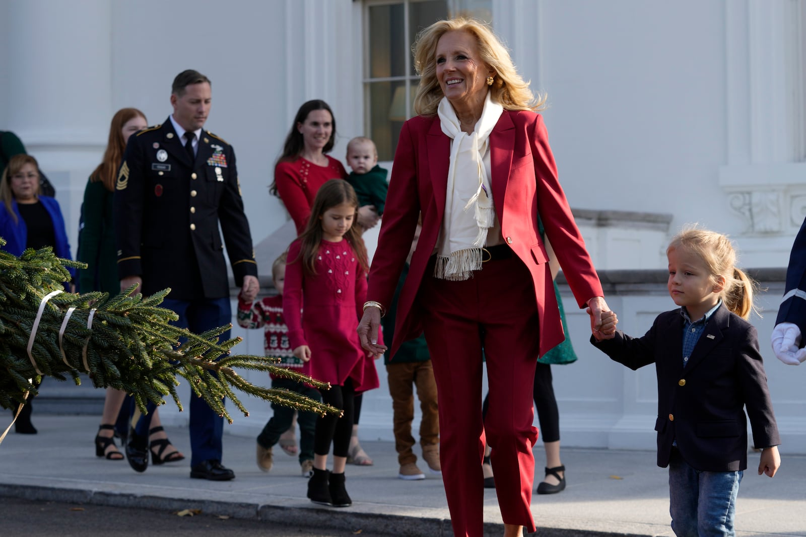 First lady Jill Biden, second right, walks with her grandson Beau Biden, right, to receive the official 2024 White House Christmas Tree on the North Portico of the White House in Washington, Monday, Nov. 25, 2024. Cartner's Christmas Tree Farm from Newland, N.C., provided the Fraser fir that will be displayed in the Blue Room of the White House. (AP Photo/Susan Walsh)