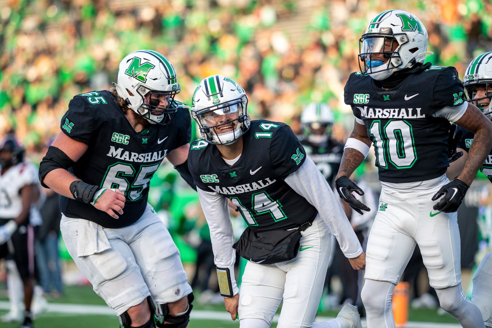 Marshall quarterback Cam Fancher (14) celebrates after a touchdown with teammates Logan Osburn (65) and Chuck Montgomery (10) during an NCAA college football game against Arkansas State, Saturday, Nov. 25, 2023, in Huntington, W.Va. (Sholten Singer/The Herald-Dispatch via AP)