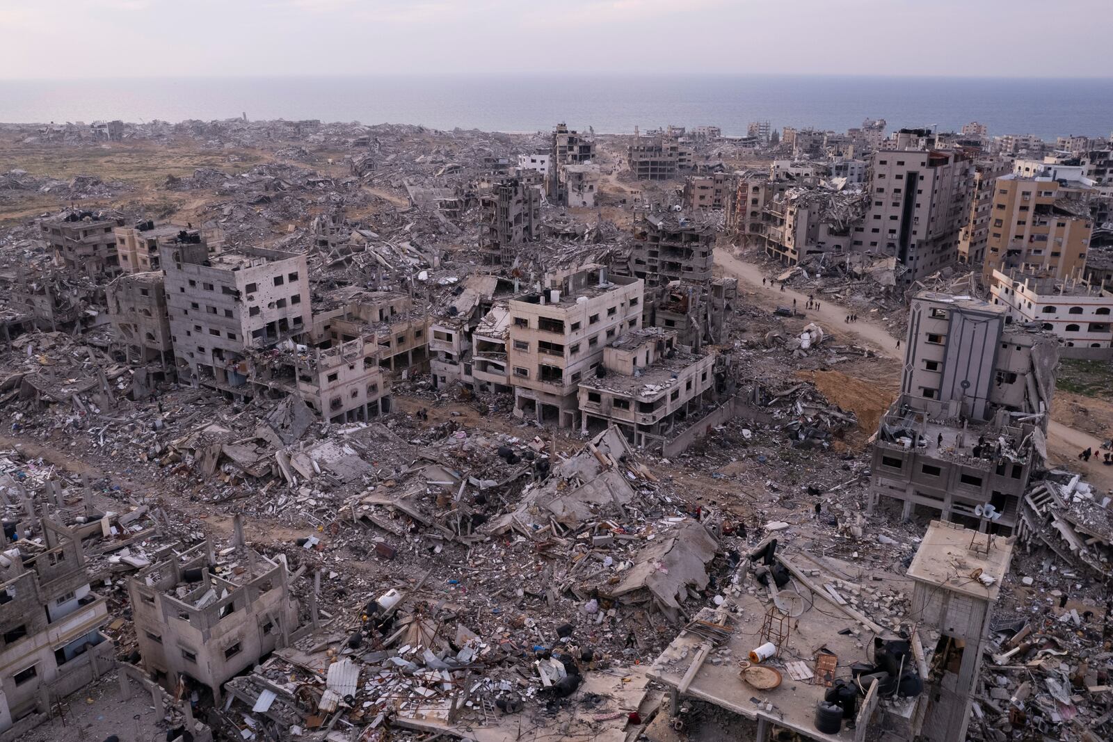 Palestinians walk through buildings that were destroyed by the Israeli air and ground offensive are seen at the Tel al-Hawa neighbourhood in Gaza Strip, Tuesday, Jan. 28, 2025. (AP Photo/Mohamamd Abu Samra)