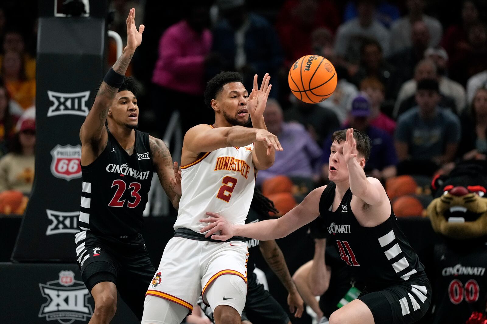 Iowa State's Joshua Jefferson (2) passes as Cincinnati's Dillon Mitchell (23) and Simas Lukosius (41) defend during the first half of an NCAA college basketball game in the second round of the Big 12 Conference tournament, Wednesday, March 12, 2025, in Kansas City, Mo. (AP Photo/Charlie Riedel)