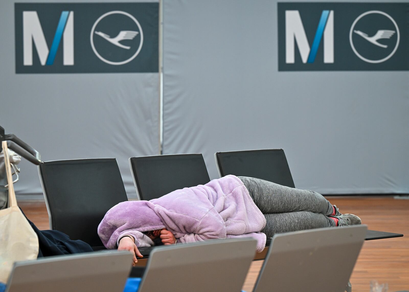 A woman sleeps on a bench in the check-in area of Terminal 2 at Munich Airport, Germany Monday, March 10, 2025. (Peter Kneffel/dpa via AP)