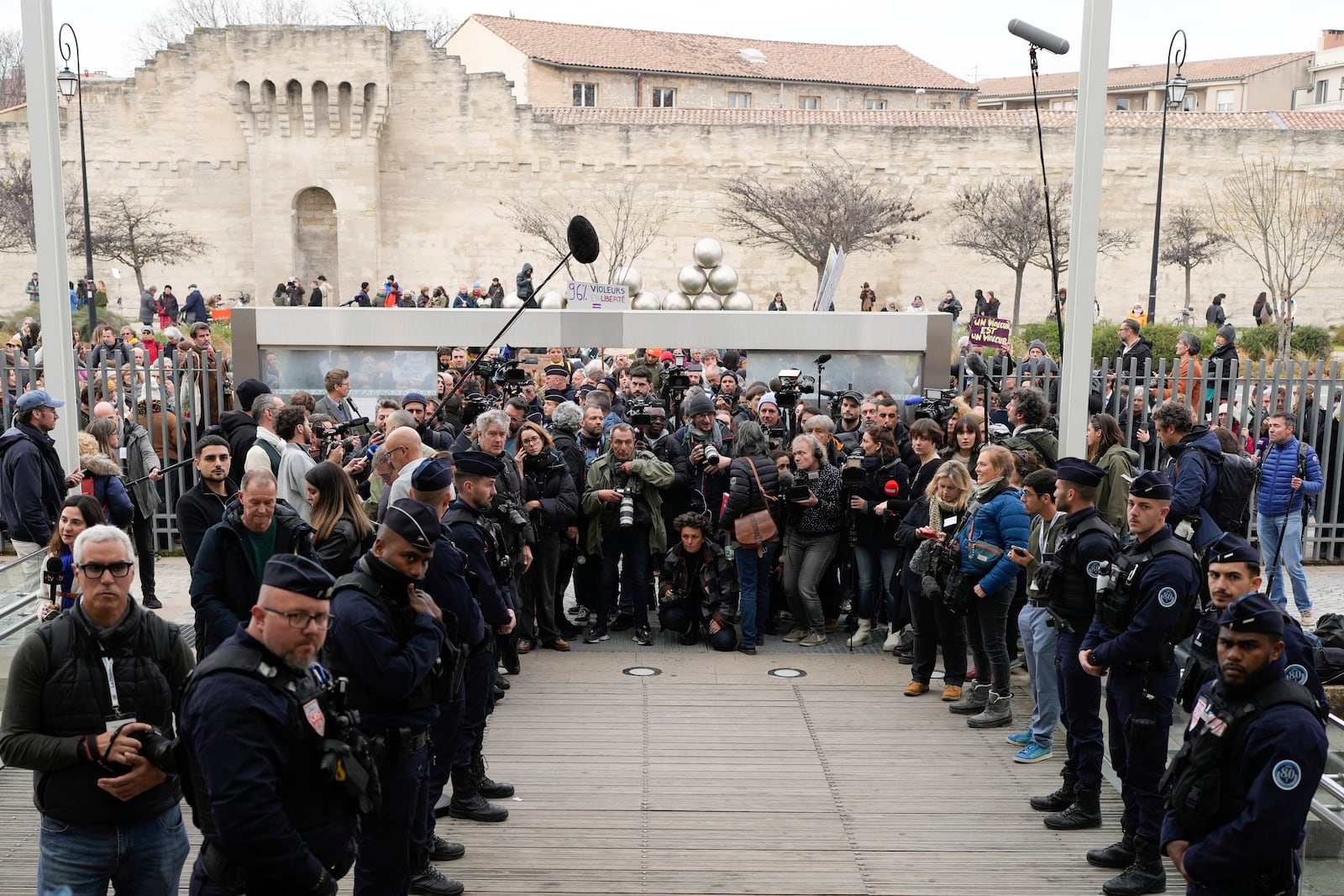 Journalists and police officers stand by while waiting for Gisele Pelicot to come out outside the Avignon courthouse, southern France, Thursday, Dec. 19, 2024. (AP Photo/Lewis Joly)