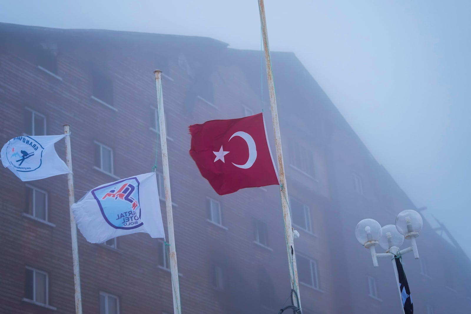 A Turkish flag flag flies at half staff outside a hotel where a fire broke out at the Kartalkaya ski resort in Bolu province, northwest Turkey, on Wednesday, Jan. 22, 2025. (AP Photo/Francisco Seco)