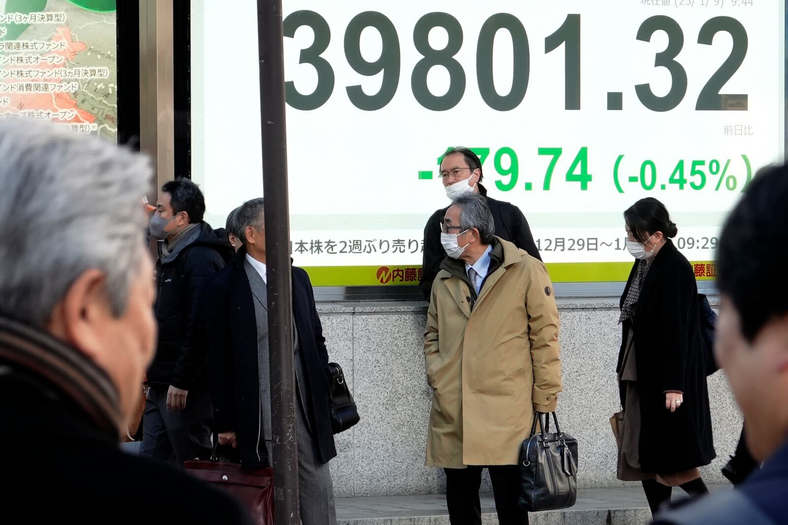 People stand near an electronic stock board showing Japan's Nikkei index at a securities firm Thursday, Jan. 9, 2025, in Tokyo. (AP Photo/Eugene Hoshiko)