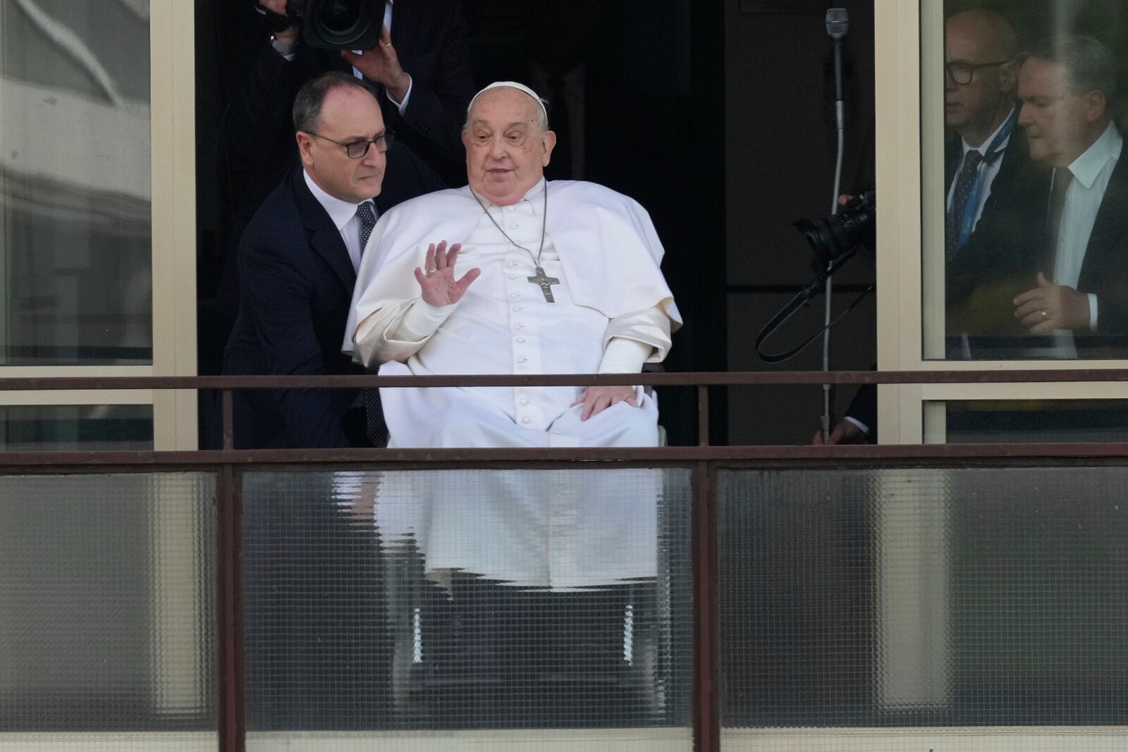 Pope Francis waves as he appears at a window of the Agostino Gemelli Polyclinic in Rome, Sunday, March 23, 2025, where he has been treated for bronchitis and bilateral pneumonia since Feb. 14. (AP Photo/Andrew Medichini)