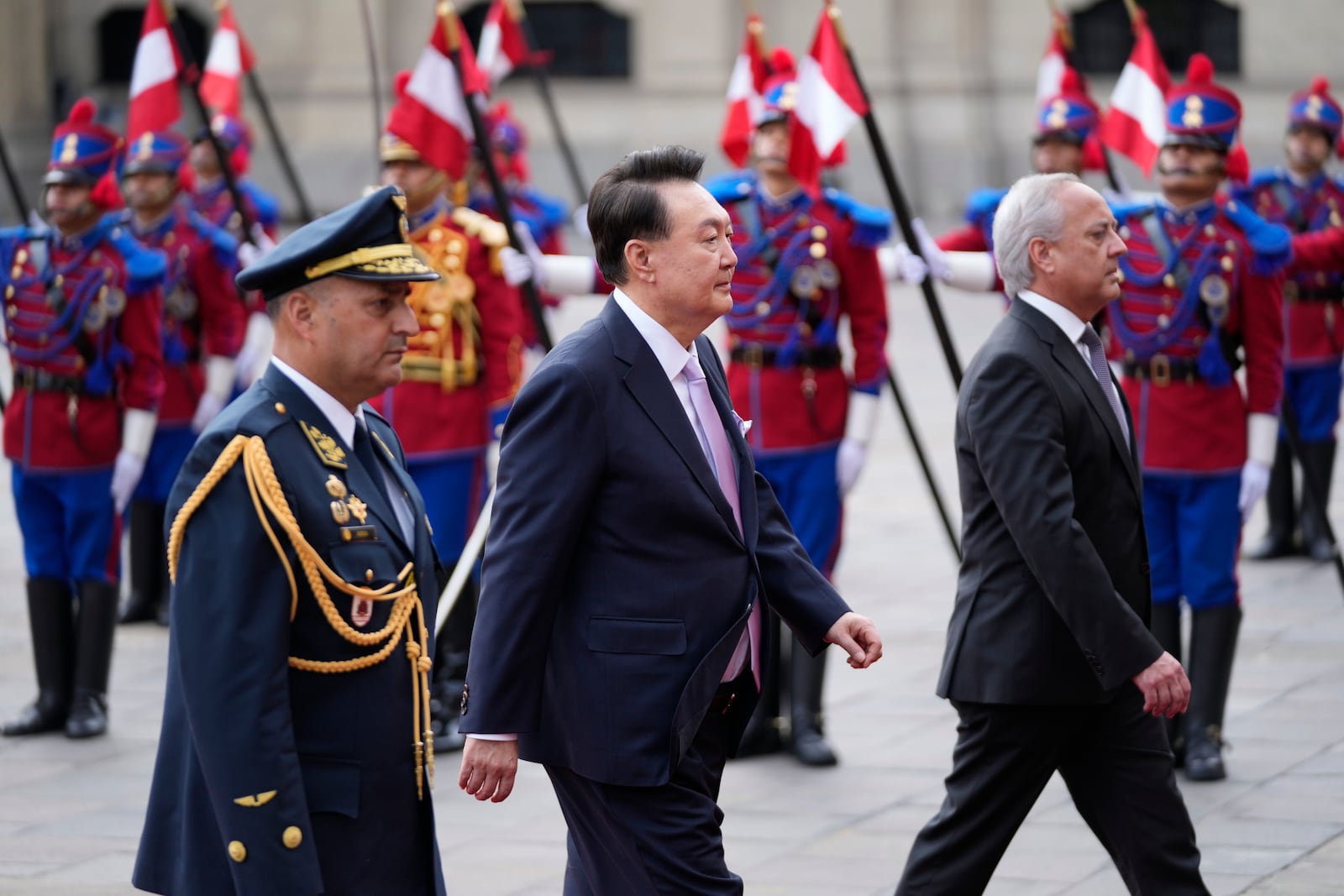 South Korea's President Yoon Suk Yeol, center, is escorted past the honor guard during a welcoming ceremony at the government palace in Lima, Peru, Saturday, Nov. 16, 2024, following the closing of the Asia-Pacific Economic Cooperation (APEC) summit. (AP Photo/Fernando Vergara)