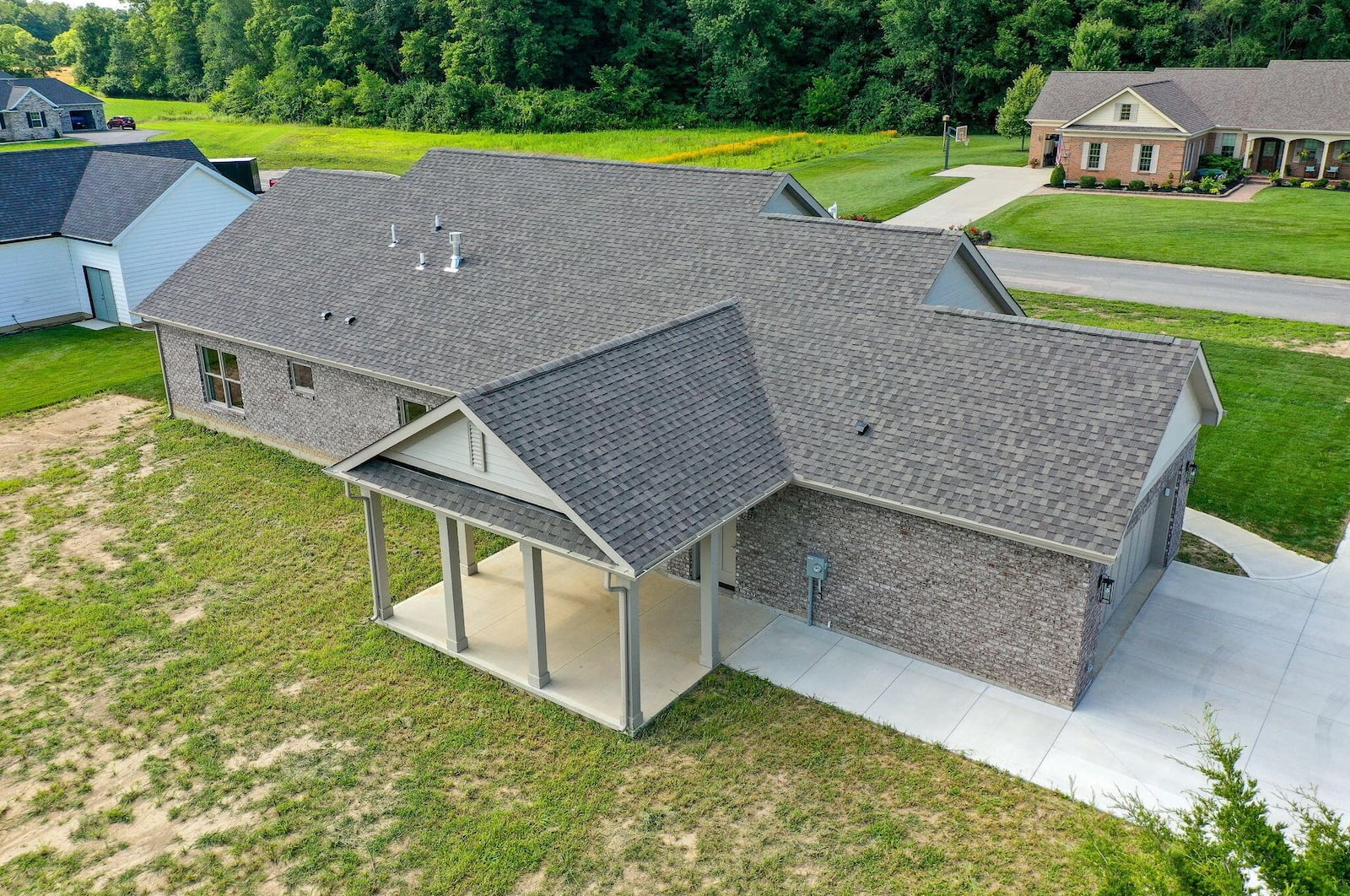 The rear of the home has a covered patio with ceiling fan and a concrete walkway connecting it to the driveway.