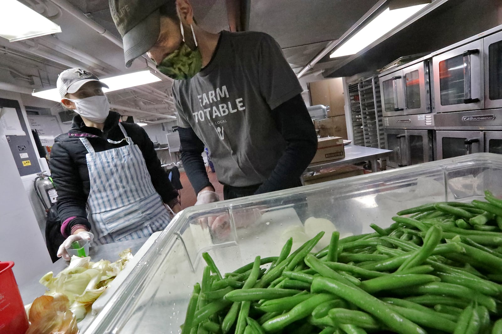 Doug McGregor and Margaret Mattox, owners of Season's Kitchen, work on carryout meals in the shared kitchen in the Bushnell Building last year. BILL LACKEY/STAFF