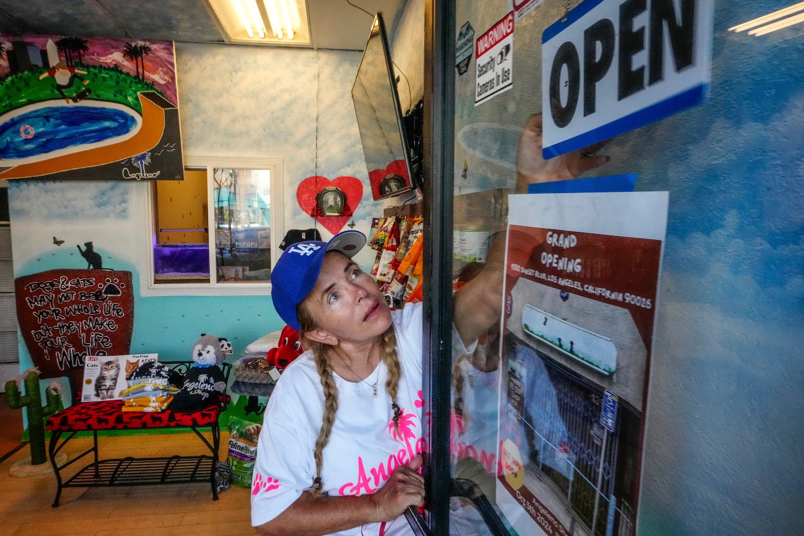 Business owner Silvia Navarro, who recently opened a dog and cat food supply store, adjusts a sign at her store in Los Angeles on Oct. 11, 2024. (AP Photo/Damian Dovarganes)