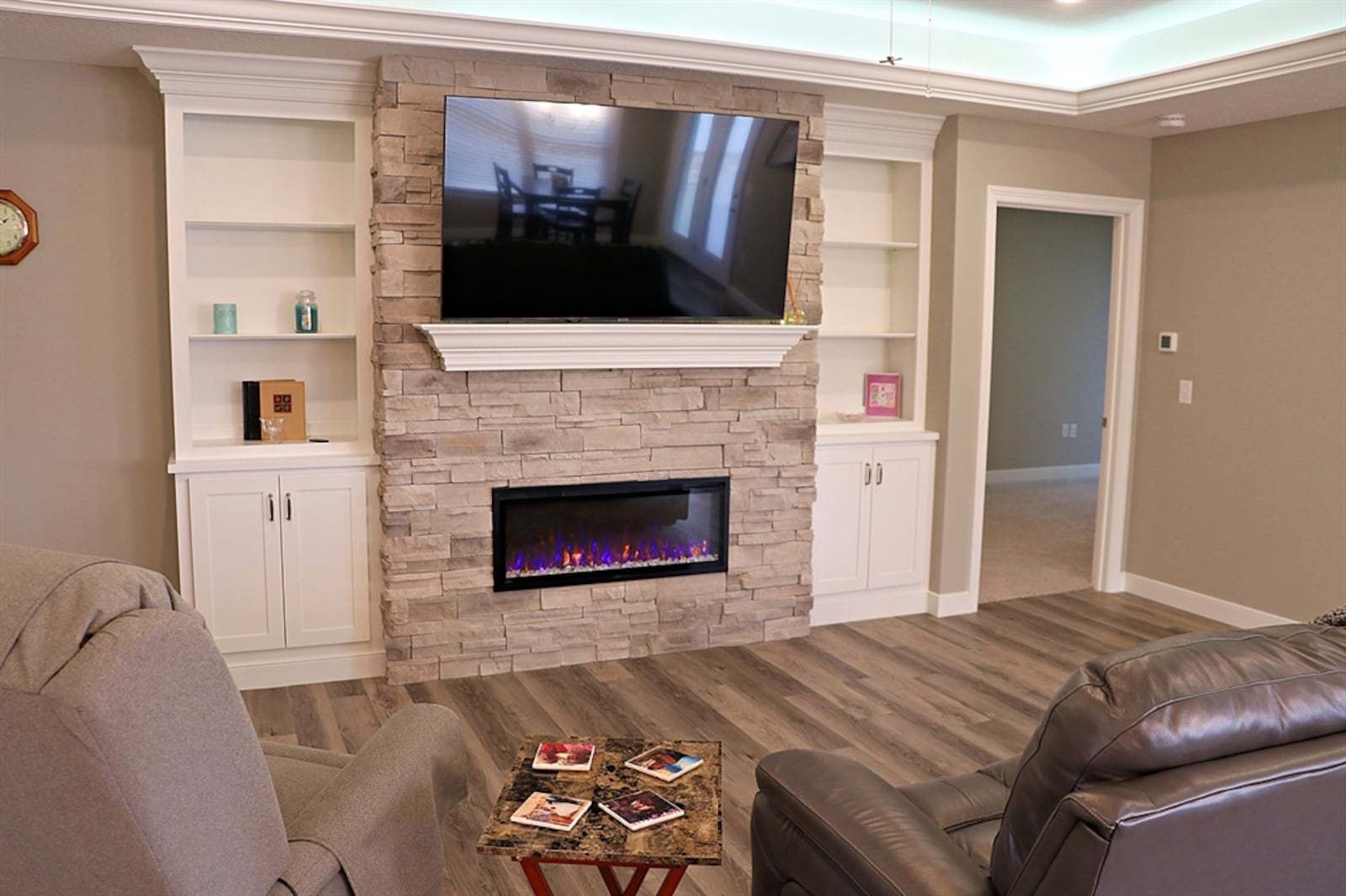 The centerpiece to the great room is a stone electric fireplace with a wood-beam mantel that is wired for media equipment. Flanking the fireplace is built-in cabinetry with open bookcase and storage cabinets.