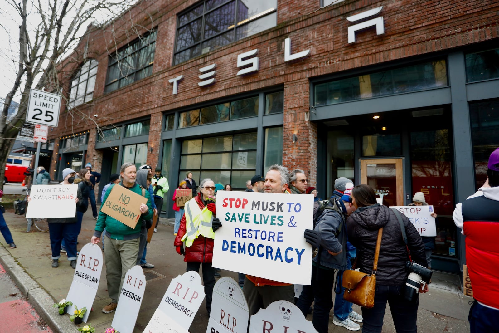 FILE - People protesting Elon Musk's actions in the Trump administration hold signs outside a Tesla showroom in Seattle on Thursday, Feb. 13, 2025. (AP Photo/Manuel Valdes, File)