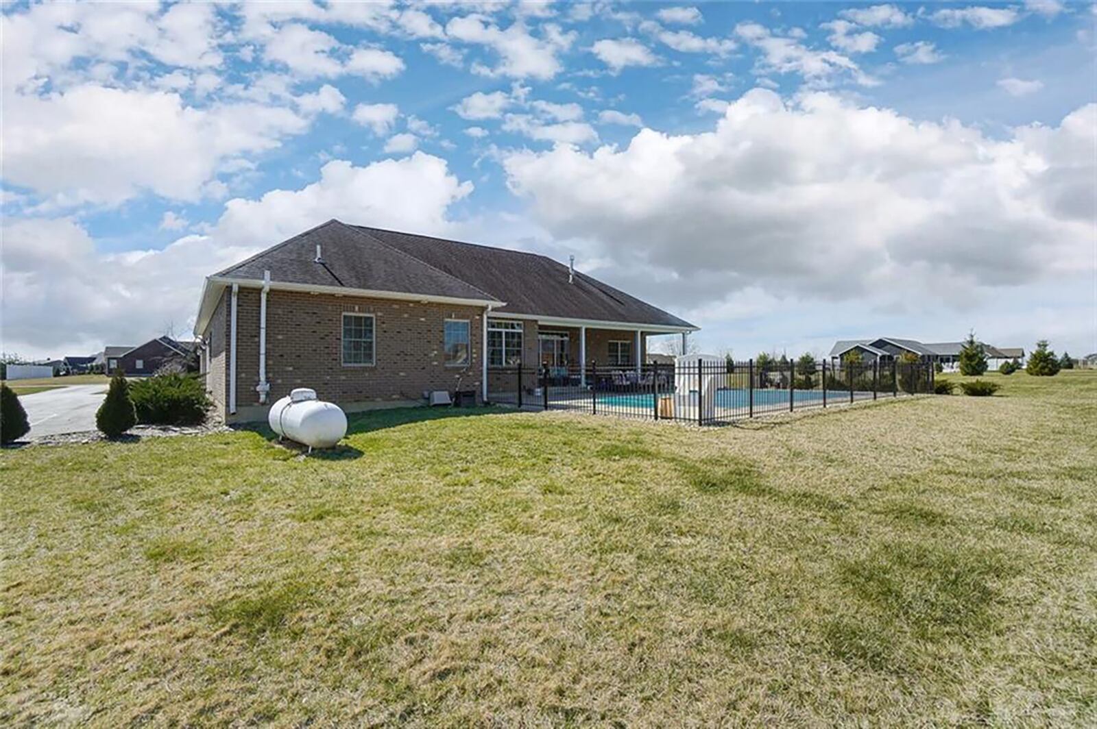 The rear of the home has a fenced, heated in-ground pool, patio with paver extensions and covered area.