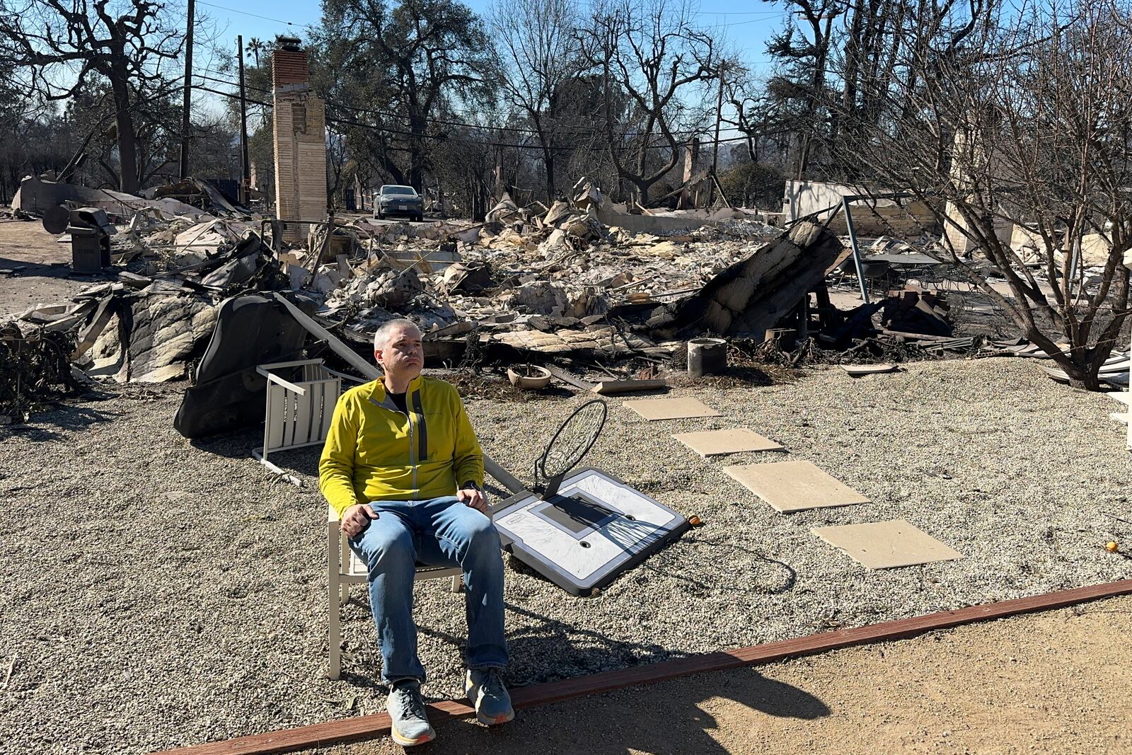 Ryan Pearson, a Los Angeles-based entertainment video editor for The Associated Press, sits in front of his home that was destroyed by the Eaton Fire in Altadena, Calif., Wednesday, Jan. 15, 2025. (AP Photo/Ryan Pearson)