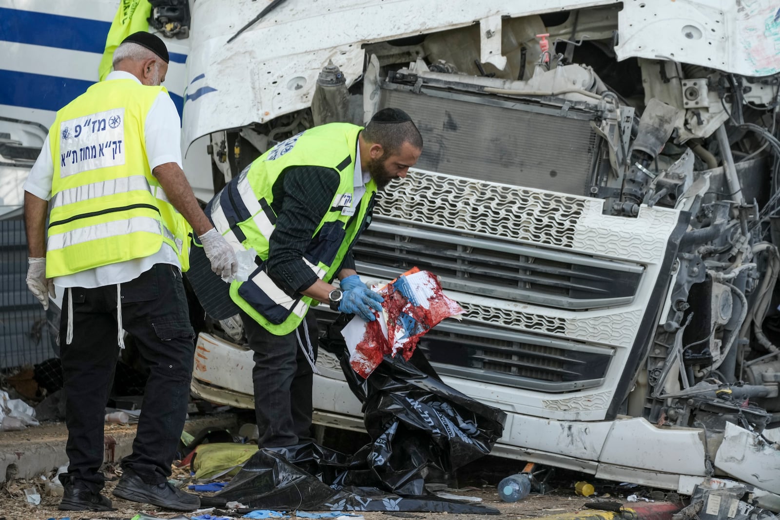 Members of Zaka Rescue and Recovery team work where a truck driver rammed into a bus stop near the headquarters of Israel's Mossad spy agency, wounding dozens of people, according to Israel's Magen David Adom rescue service in Tel Aviv, Israel, Sunday, Oct. 27, 2024. (AP Photo/Oded Balilty)