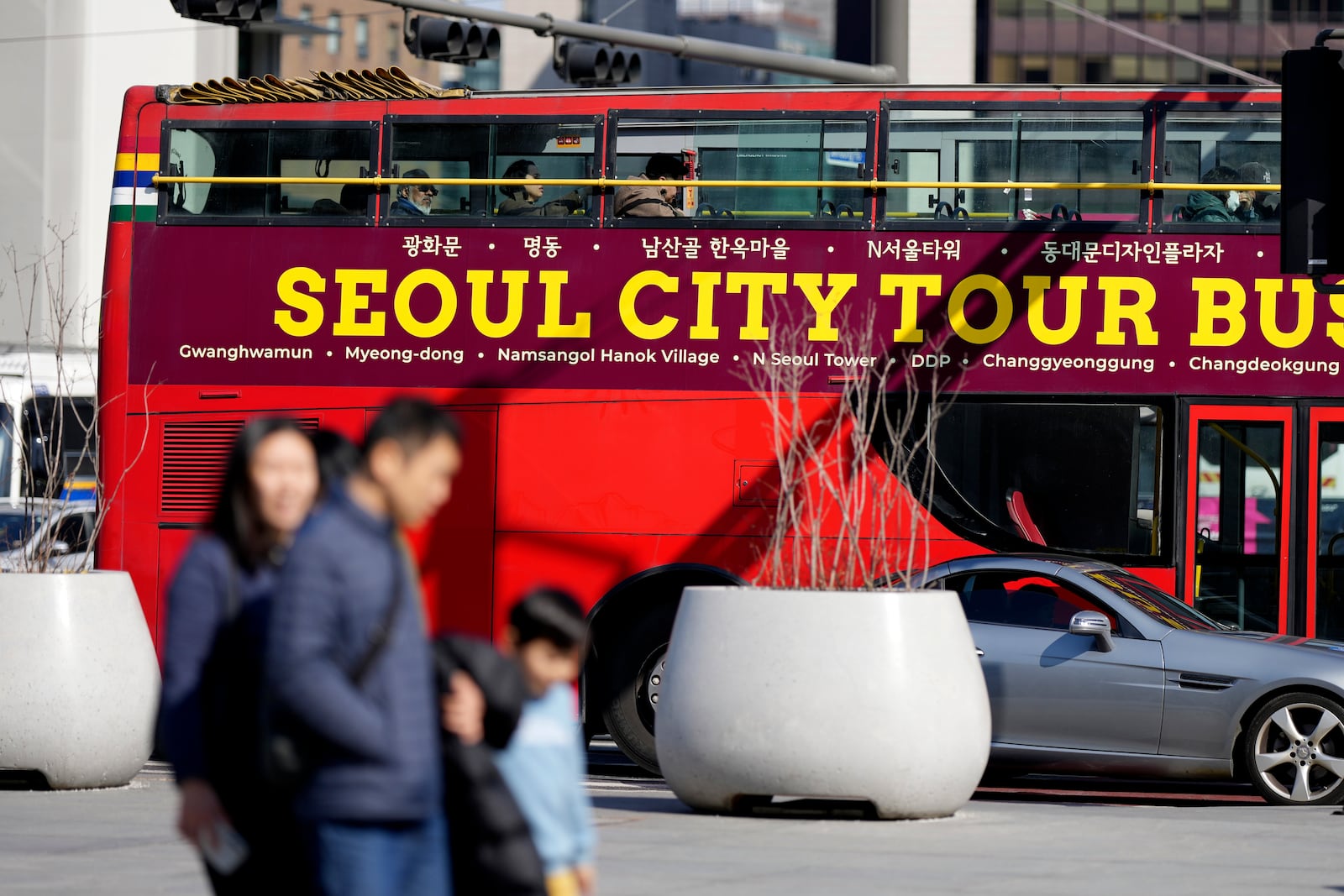 People walk near South Korea's capital Seoul tour bus in Seoul, South Korea, Thursday, Feb. 27, 2025. (AP Photo/Lee Jin-man)