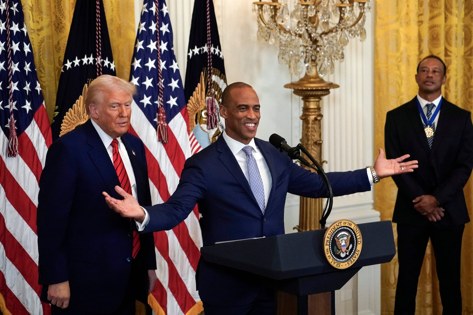 Housing and Urban Development Secretary Scott Turner speaks as President Donald Trump and Tiger Woods listen during a reception for Black History Month in the East Room of the White House Thursday, Feb. 20, 2025. (Pool via AP)