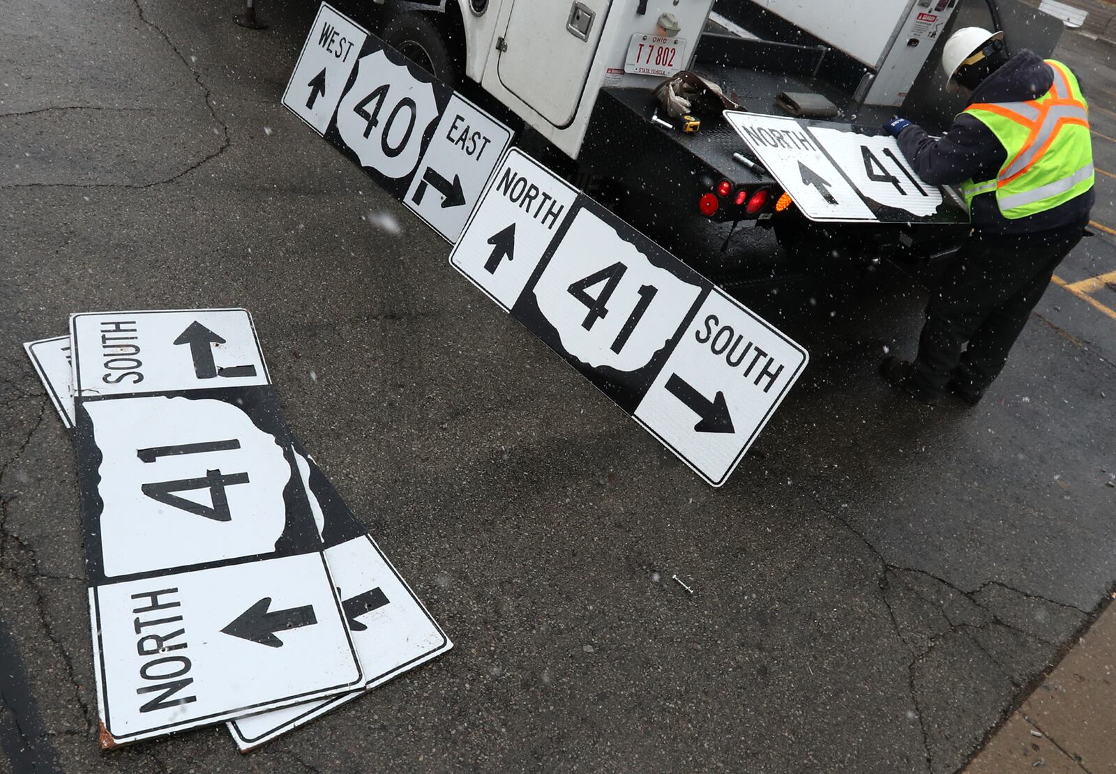 An ODOT worker swaps out old direction signs for new signs at the intersection of US 40 and Ohio Route 41 Friday along Spring Street in Springfield. BILL LACKEY/STAFF