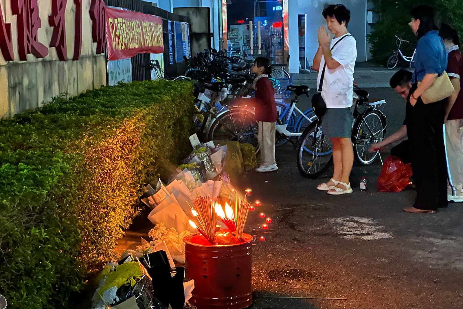 A woman prays after incense were offered near flowers placed outside the Zhuhai People's Fitness Plaza, where a man deliberately rammed his car into people exercising at the sports center, killing some and injuring others in Zhuhai in southern China's Guangdong province on Tuesday, Nov. 12, 2024. (AP Photo/Ng Han Guan, File)