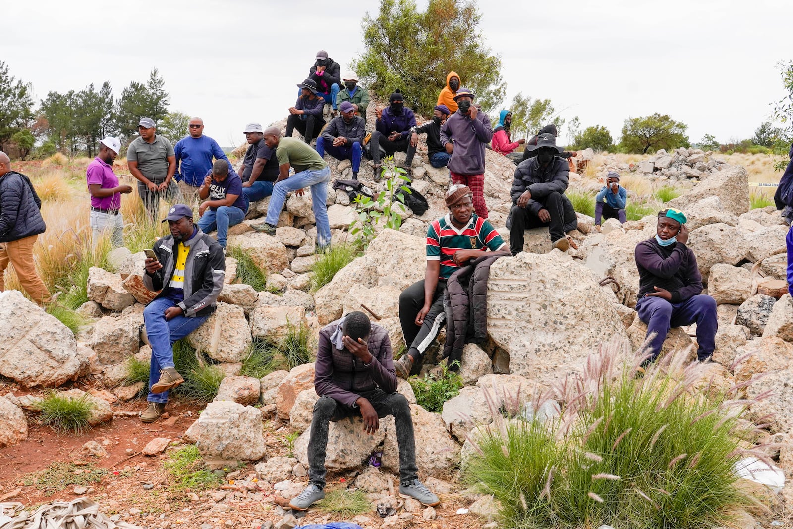 Volunteer rescuers sit by the opening of a reformed gold mineshaft where illegal miners are trapped in Stilfontein, South Africa, Friday, Nov. 15, 2024. (AP Photo/Denis Farrell)