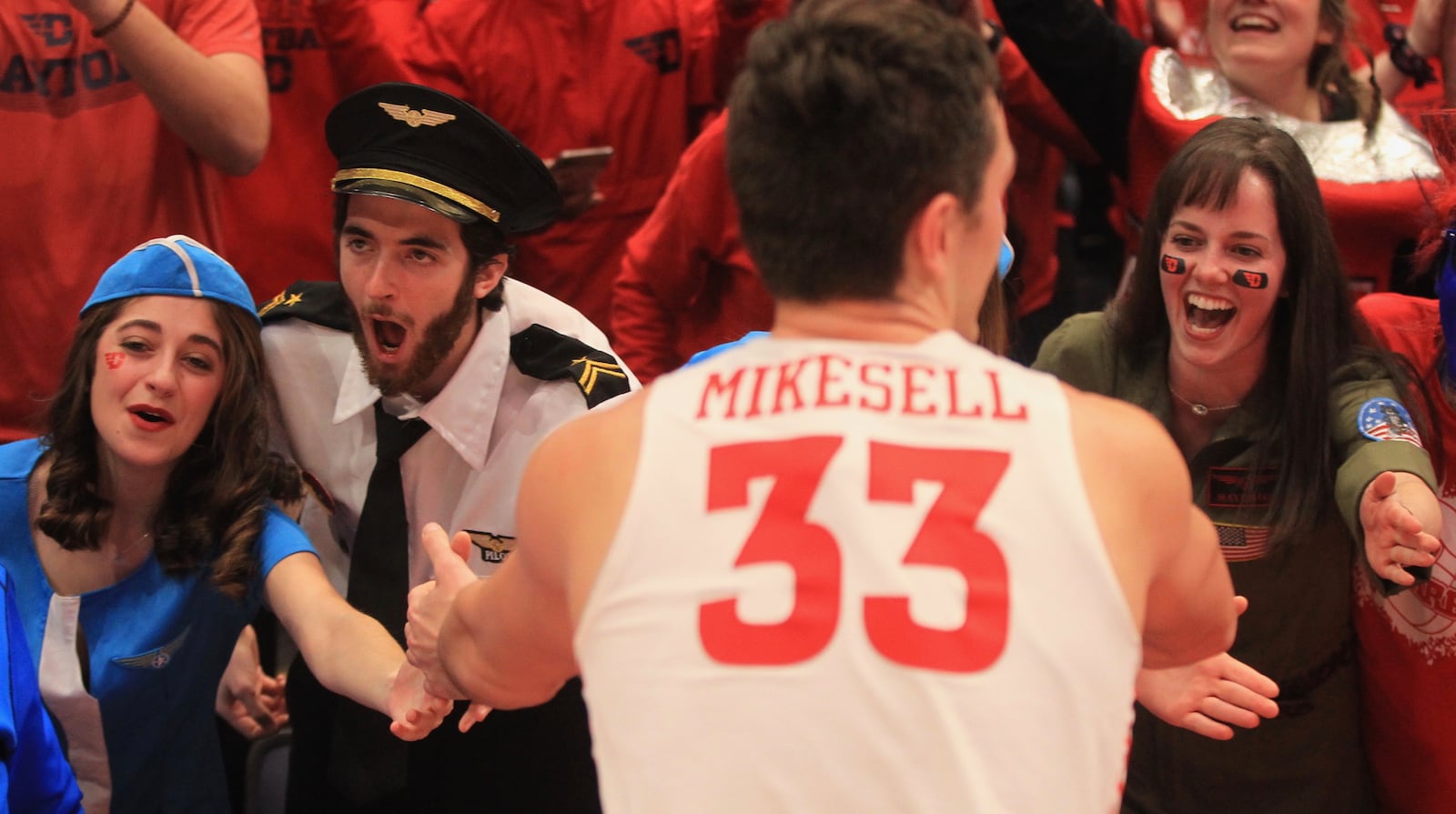 Members of the Red Scare slap hands with Ryan Mikesell after Dayton's victory against Davidson on Feb. 28, 2020, at UD Arena. Pictured (left to rightI are:  Annie Montefiori, Michael Oliver and Michelle Smith.