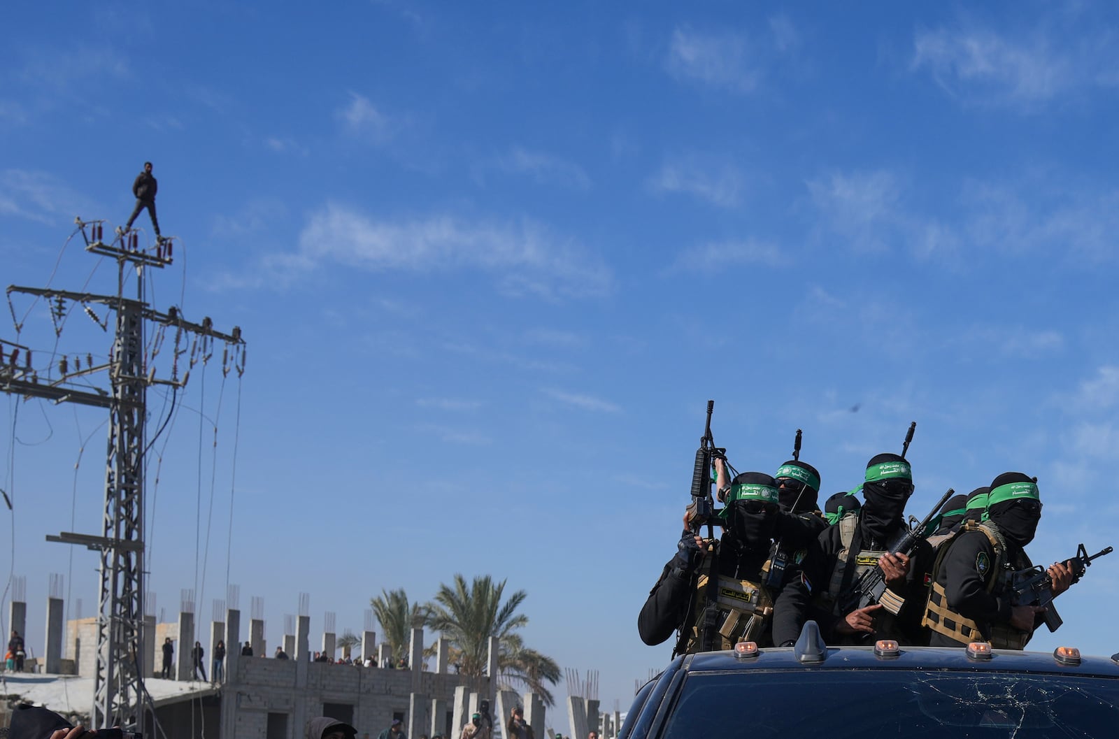 Hamas fightersstand on a pick up truck as they arrive for the handover of Israeli captives Iair Horn, Alexander (Sasha) Troufanov, and Sagui Dekel Chen to the Red Cross in Khan Younis, Gaza Strip, Saturday, Feb. 15, 2025. (AP Photo/Abdel Kareem Hana)