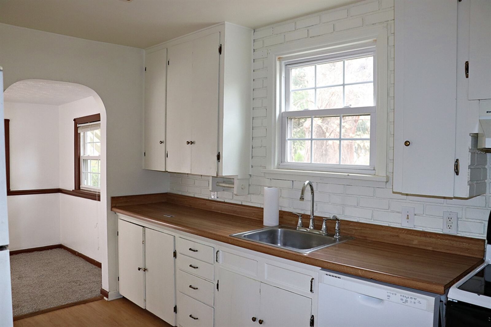 Accessible from the dining room, the galley kitchen has painted white cabinetry, including a baking center with spice cabinets and drawers. 