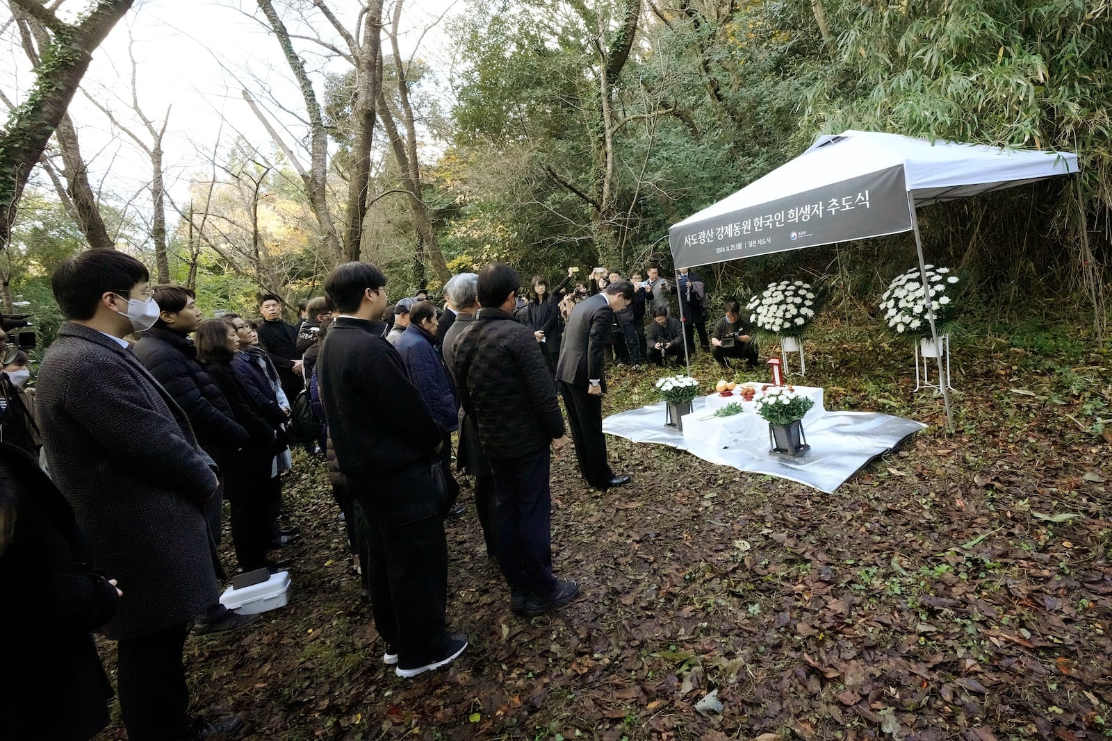 South Korean Ambassador to Japan Park Cheol-hee, right, bows to an altar as the relatives of Korean victims and South Korean officials during a memorial service at the site of former Fourth Souai Dormitory for the mine workers from the Korean Peninsula, in Sado, Niigata prefecture, Japan, Monday, Nov. 25, 2024. (AP Photo/Eugene Hoshiko)