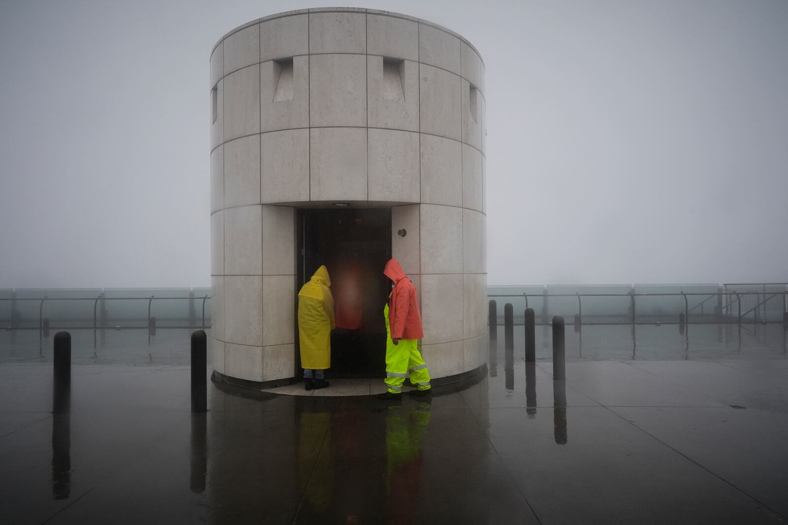 Workers shield themselves from the rain at the Griffith Park Observatory Thursday, Feb. 13, 2025, in Los Angeles. (AP Photo/Damian Dovarganes)