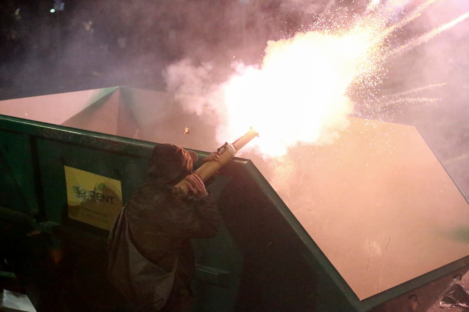 A demonstrator fires a firecracker towards police as police block a street to prevent protesters rallying against the government's decision to suspend negotiations on joining the European Union for four years, outside the parliament's building in Tbilisi, Georgia, early Sunday, Dec. 1, 2024. (AP Photo/Zurab Tsertsvadze)